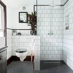 a white toilet sitting next to a shower in a bathroom under a mirror on the wall