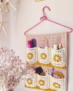 a crocheted purse hanging on a wall next to a potted plant and starfish