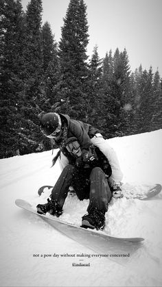 a man riding a snowboard down the side of a snow covered slope with trees in the background