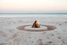 there is a fire pit made out of sand on the beach