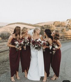 the bridesmaids are all dressed in burgundy dresses and bouquets for their wedding