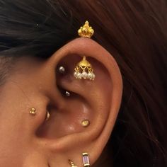 a close up of a person wearing ear piercings with gold colored beads on their ears