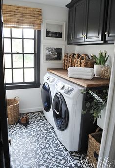 a washer and dryer sitting in a room next to a window with black cabinets