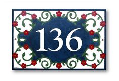 a blue and white house number plaque with red flowers