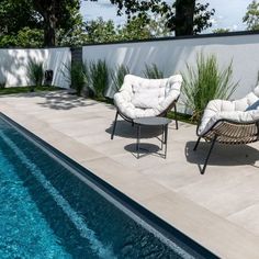 two chairs sitting next to a swimming pool