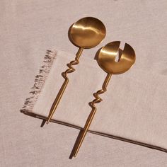 two gold spoons sitting on top of a white cloth