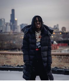 a man with dreadlocks standing in front of a city skyline