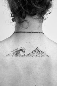 a woman's back with a wave tattoo on it