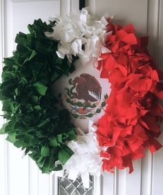 two wreaths on the front door decorated with red, white and green tissue paper