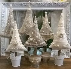 four white christmas trees sitting on top of a wooden table