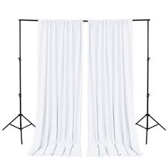 two white curtains with black stands against a white background