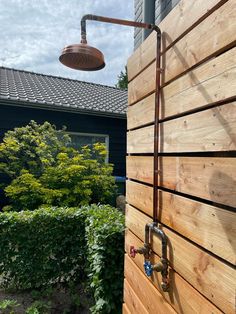 an outdoor shower head mounted to the side of a wooden wall