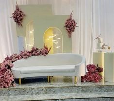 a white couch sitting on top of a table covered in pink flowers and greenery