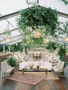 an outdoor wedding venue with couches, tables and greenery hanging from the ceiling