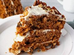 a piece of carrot cake with white frosting and pecans on the top slice