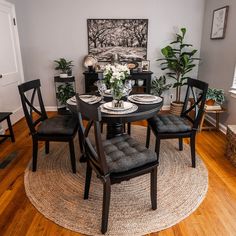 a dining room table set with four chairs and a round rug in front of it