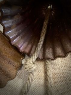 an umbrella with rope attached to it sitting on the ground next to a pillow and blanket