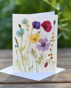 a card with flowers on it sitting on top of a wooden table