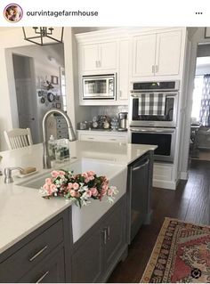 a white kitchen with gray cabinets and an area rug on the floor in front of the sink