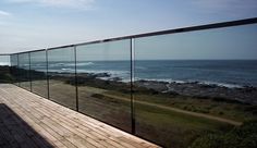 a wooden deck with glass railing overlooking the ocean