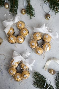 christmas cookies and candy wrapped in white ribbon next to pine cones, bells and ornaments