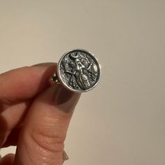 a person is holding a silver ring with a coin on the front and back of it