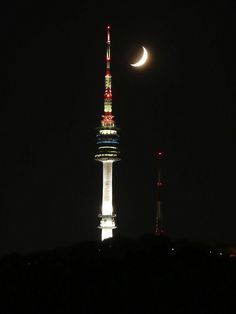 the moon is seen over a tall tower at night