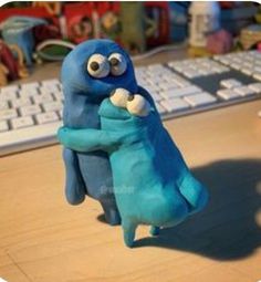 a blue stuffed animal sitting in front of a keyboard