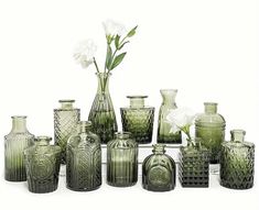 a group of green vases with white flowers in them