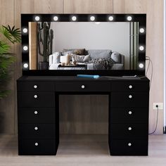 a black vanity table with lights on it and a couch in the backround