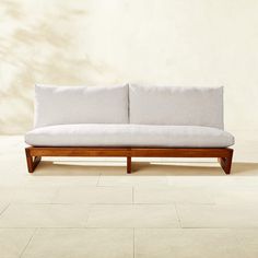 a white couch sitting on top of a tile floor next to a wooden frame chair