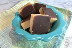 several pieces of brown and white chocolate in a blue bowl on a green plate with a yellow towel