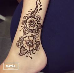 a woman's foot with a henna tattoo on her left leg and flowers on the right side