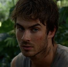 a close up of a person in front of some trees and plants with blue eyes