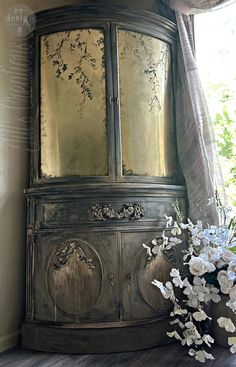 an old china cabinet with flowers in front of it