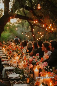 a long table is set with candles and flowers for an outdoor dinner party in the woods