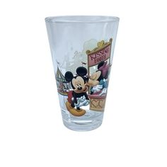 a glass with mickey mouse and other disney characters on the side, sitting in front of a white background