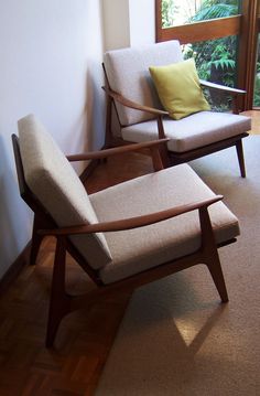 two chairs sitting next to each other in a room with wood flooring and windows