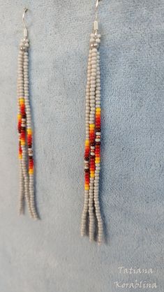 two white and orange beaded earrings hanging from hooks