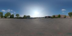 the sun shines brightly over an empty parking lot in front of some buildings and trees