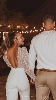 a man and woman holding hands while standing next to each other on a dance floor