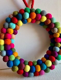 a multicolored felt wreath hanging on a wall