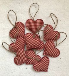 small red and white gingham hearts tied to twine on a white surface