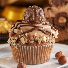 there is a cupcake with chocolate frosting and nuts on the plate next to it