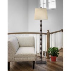 a living room with a chair, lamp and potted plant on the floor in front of it