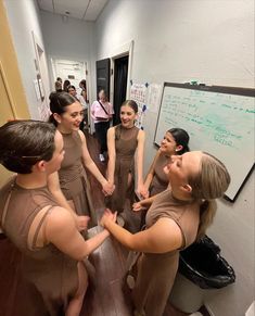 several women in brown dresses standing around each other