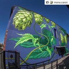 a mural on the side of a building with green leaves and flowers painted on it