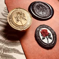 three buttons with roses on them are sitting on a piece of fabric