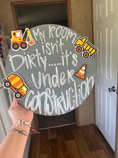 a person holding up a sign that says, my room isn't dirty it's under construction