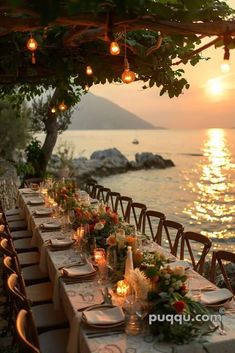 an outdoor dining table with candles and flowers on it at sunset overlooking the ocean in italy